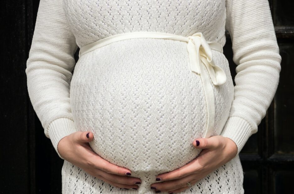 pregnant woman holding her tummy during daytime